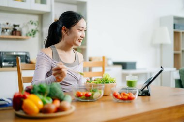 Mutfakta genç bir kadın ve evde sağlıklı yemek tarifi ya da günlük diyet yazıyor. Aktif sağlıklı yaşam tarzı, temiz yeme konsepti