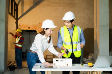 Çalışma ve tablet hakkında konuşan iki meslektaşım, ofisteki inşaat alanında mimari projeli dizüstü bilgisayar.