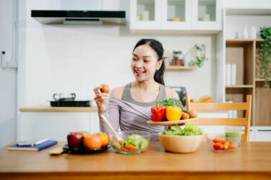 Mutfakta genç bir kadın ve evde sağlıklı yemek tarifi ya da günlük diyet yazıyor. Aktif sağlıklı yaşam tarzı, temiz yeme konsepti