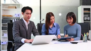 Parlak, modern bir ofiste kağıt üzerinde çalışan çeşitli profesyonellerden oluşan bir grup..