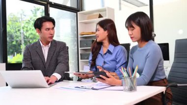 Motive olmuş genç ofis çalışanları grup toplantısı sırasında belgeleri incelerken görüşlerini paylaşıyorlar.