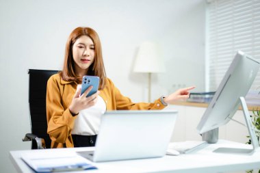 Modern ofis çalışma alanında dizüstü bilgisayar, tablet ve telefon kullanan kendine güvenen Asyalı iş adamları, veri stratejisi ve başarı planlıyorlar. Teknoloji, takım çalışması ve büyüme kavramı