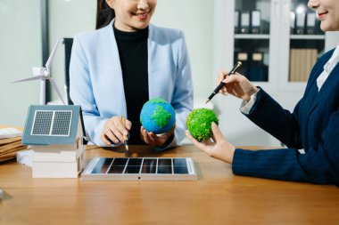 İki kadın ekolojik dünya modellerini, güneş panellerini ve yenilenebilir enerji çözümlerini planlamak için akıllı bir evi analiz ediyor. 