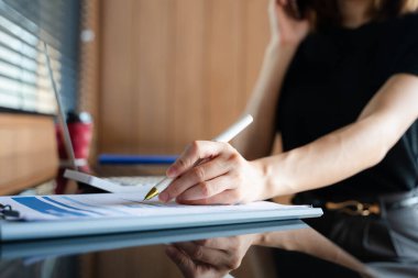 Modern bir çalışma alanında akıllı telefon ve dizüstü bilgisayar kullanan Asyalı iş kadını, dijital iletişim, verimlilik ve profesyonel uzaktan kumandayı sergiliyor..