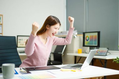 Kadın, modern bir yaratıcı ofiste tablet üzerinde çalışırken başarıyı kutluyor. Başarı, keyif ve dijital serbest yaşam tarzını yakalıyor..