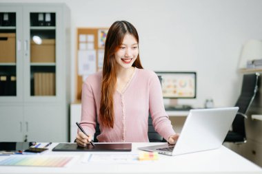 Modern ofiste dijital tablet ve laptop kullanan genç bayan grafik tasarımcısı. Yaratıcı çalışma alanı, renk paletleri ve UI UX tasarımı devam ediyor. Tasarım temaları için ideal