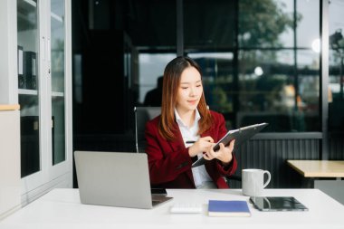 Asyalı iş kadını ofisteki panoya notlar yazıyor. 