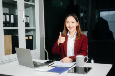 Ofiste çalışırken gülümseyen iş kadını başparmağını kaldırıyor 