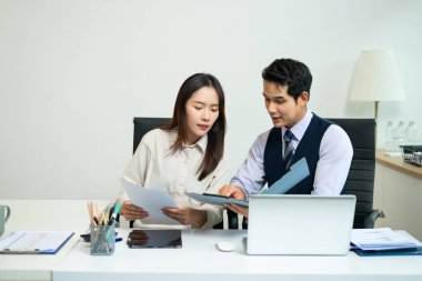Business colleague business presents and explains and using laptop and tablet. Teamwork, financial marketing team, while sitting in office