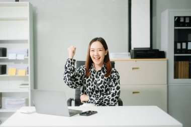 Genç Asyalı iş kadını gülümsüyor ve ofiste tablet ve dizüstü bilgisayarla çalışıyor. Vergi, rapor, muhasebe ve istatistiksel analiz kavramı. 