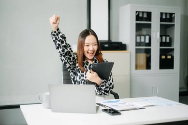  Neşeli iş kadını, kendini motive olmuş hissediyor. Ofisten ayrılmayı bekliyor. Tabletlerini, laptoplarını alıyor ve not alıyor.