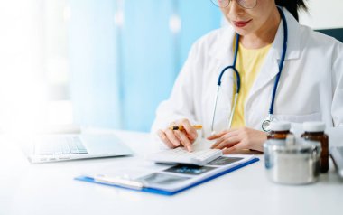 Sağlık masrafları ve ücretleri kavramı. Akıllı doktor el sabah ışık Hastanesi'nde sağlık giderleri için bir hesap makinesi ve akıllı telefon, tablet kullanılan