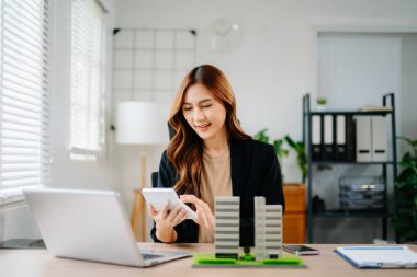 Emlak komisyoncusu, emlak kredisi teklifiyle ilgili sözleşme imzalama anlaşmasını, ev modelini sunar ve müşteriye danışmanlık yapar.