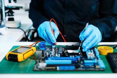 Bilgisayar anakartını hassas aletlerle lehimleyen teknisyenlerin kapatılması, elektronik onarım, donanım teknolojisi ve yenilikler
