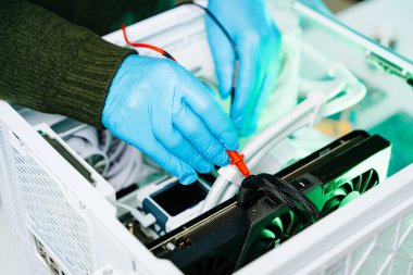 GPU 'yu eldiven ve aletlerle test eden teknisyenlerin yakın çekimi. Bilgisayar onarımı, tanı, donanım bakımı ve teknoloji mühendisliği hizmetleri kavramı.
