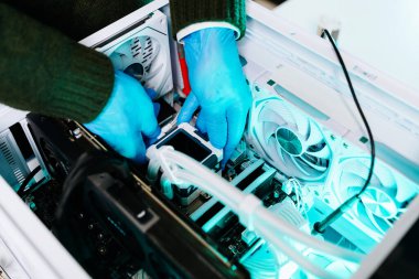 İşlemci eldivenli teknisyen özel bilgisayara sıvı soğutucu yerleştiriyor. Modern çalışma alanında bilgisayar onarımı, donanım montajı, mühendislik ve teknoloji bakımı kavramı.