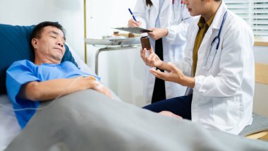 Doktor ve hemşire hastane yatağında kıdemli bir hastaya danışarak, tedavi ve tedaviyi tartıştılar. Bakım sağlık ekibi hastanın iyileşmesini ve sağlığını destekliyor.