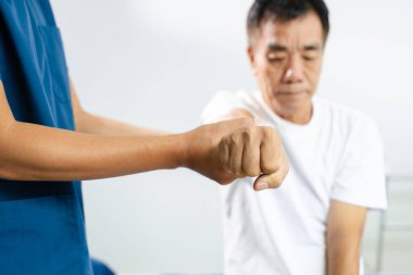 Erkek fizyoterapist, kol hareketliliği ve bilek hareketi eğitiminde kıdemli erkek hastayı destekliyor. Felç rehabilitasyonu, yaşlı bakımı ve klinik ortamında fizik tedavi