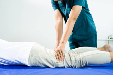 Erkek fizyoterapist, rehabilitasyon sırasında hastaya bacak ve ayak bileğini esnetme konusunda yardımcı oluyor. Klinik ortamlarda tıbbi bakım, eklem hareket kabiliyeti ve fizik tedavi