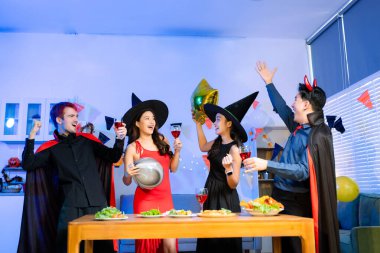 Cadılar Bayramı 'nda cadılar ve şeytanlar gibi giyinmiş arkadaşlarla neşeli bir cadılar bayramı kutlaması, pizza paylaşımı, kahkaha ve canlı kapalı bir parti sahnesinde şenlikli içecekler..