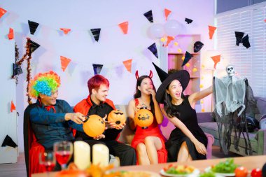 Cadı, palyaço, şeytan ve vampir kostümlü neşeli arkadaşlar güler, beşlik çakar ve Cadılar Bayramı partisinde balkabağı feneri, yiyecek ve içeceklerle kutlarız..