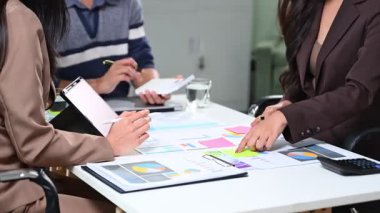 Parlak bir ofiste pazarlama verilerini tartışan bir grup genç profesyonel.