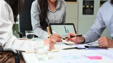 Bir tabletteki veri tablosunu analiz eden bir grup iş adamı