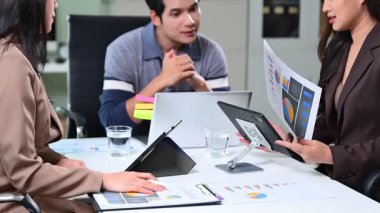 Şirket ekibi, ofisteki tablet ve kağıtta mali tabloları analiz ediyor.