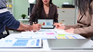 İş dünyası analistleri dijital tablette renkli finansal grafikleri inceliyor