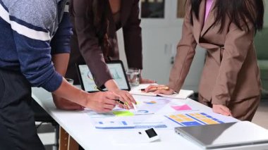 İş dünyası analistleri dijital tablette renkli finansal grafikleri inceliyor