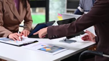 Şirket ekibi, ofisteki tablet ve kağıtta mali tabloları analiz ediyor.