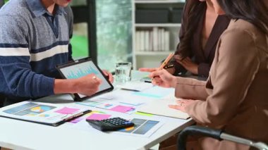 Ofisteki dijital tablette finansal veri ve grafikleri gösteren profesyonel bir ekip