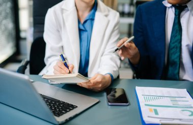 Ofis masasında akıllı telefon ve hesap makinesi olan iş belgeleri dijital tablet ve sosyal ağ diyagramı olan grafik işleri ve ofiste çalışan iki iş arkadaşı.