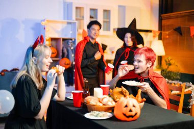 Cadılar Bayramı kostümlü bir grup genç arkadaş kapalı bir partide yemek ve içkinin tadını çıkarıyorlar. Gerçek insanlar eğlence, ürkütücü titreşimler, kırmızı bardaklar ve balkabağı dekoru ile kutluyor..