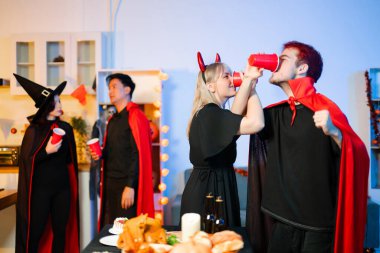 Cadılar Bayramı kostümlü bir grup genç arkadaş kapalı bir partide yemek ve içkinin tadını çıkarıyorlar. Gerçek insanlar eğlence, ürkütücü titreşimler, kırmızı bardaklar ve balkabağı dekoru ile kutluyor..