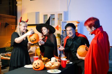 Neşeli ofis Cadılar Bayramı partisi kostüm giymiş iş arkadaşlarıyla, içkiler ve kahkahalarla kutlama, takım çalışmasını teşvik etme ve şenlik ruhu.