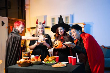 Neşeli ofis Cadılar Bayramı partisi kostüm giymiş iş arkadaşlarıyla, içkiler ve kahkahalarla kutlama, takım çalışmasını teşvik etme ve şenlik ruhu.