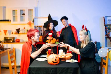 Cadılar Bayramı kostümlü genç arkadaşlar kapalı bir partide balkabağı feneri süslüyorlar. Gerçek insanlar ürkütücü titreşimleri, kırmızı bardakları, atıştırmalıkları ve Cadılar Bayramı aksesuarlarını severler..