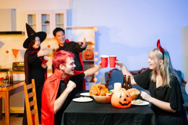 Cadılar Bayramı kostümlü bir grup genç arkadaş kapalı bir partide yemek ve içkinin tadını çıkarıyorlar. Gerçek insanlar eğlence, ürkütücü titreşimler, kırmızı bardaklar ve balkabağı dekoru ile kutluyor..