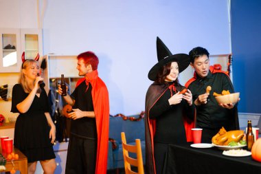 Cadılar Bayramı kostümlü genç arkadaşlar kapalı bir partide balkabağı feneri süslüyorlar. Gerçek insanlar ürkütücü titreşimleri, kırmızı bardakları, atıştırmalıkları ve Cadılar Bayramı aksesuarlarını severler..