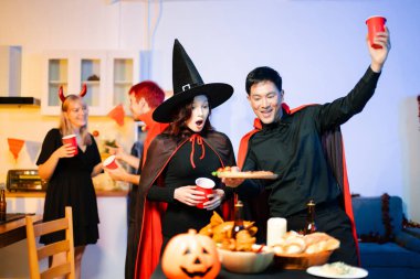 Cadılar Bayramı kostümlü genç arkadaşlar kapalı bir partide balkabağı feneri süslüyorlar. Gerçek insanlar ürkütücü titreşimleri, kırmızı bardakları, atıştırmalıkları ve Cadılar Bayramı aksesuarlarını severler..