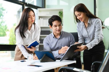 Modern ofiste takım planlaması ve tartışması için tablet ve not defterlerini kullanan genç iş adamları. Girişim, takım çalışması, gerçek insanlar, verimlilik
