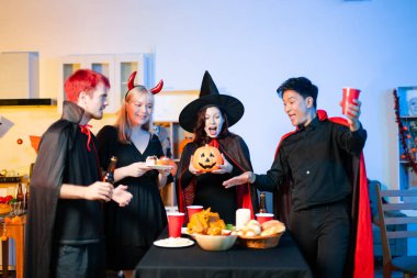 Cadılar Bayramı kostümlü bir grup genç arkadaş kapalı bir partide yemek ve içkinin tadını çıkarıyorlar. Gerçek insanlar eğlence, ürkütücü titreşimler, kırmızı bardaklar ve balkabağı dekoru ile kutluyor..