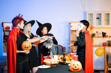 Cadılar Bayramı partisi, balkabağı ve hayalet iskelet gibi ürkütücü aksesuarlara sürpriz ve kahkahalarla tepki verir. Mükemmel mevsimlik eğlence, dekor ve şenlik havası..