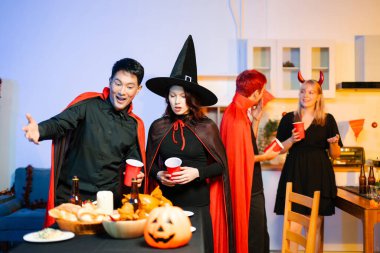 Cadılar Bayramı kostümlü genç arkadaşlar kapalı bir partide balkabağı feneri süslüyorlar. Gerçek insanlar ürkütücü titreşimleri, kırmızı bardakları, atıştırmalıkları ve Cadılar Bayramı aksesuarlarını severler..