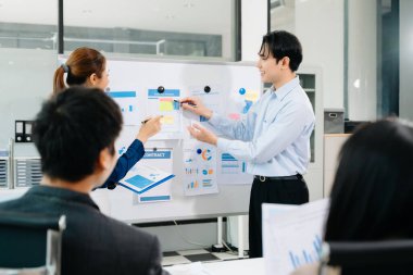 Başarılı bir toplantının ardından gülümseyen Asyalı iş adamları, modern ofis ortamında ortaklığı, takım çalışmasını ve şirket başarısını sembolize ediyor..