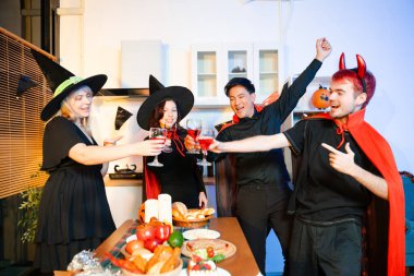 Neşeli ofis Cadılar Bayramı partisi kostüm giymiş iş arkadaşlarıyla, içkiler ve kahkahalarla kutlama, takım çalışmasını teşvik etme ve şenlik ruhu.