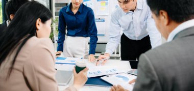 Asyalı iş adamlarının parlak modern ofiste beyin fırtınası yapıp raporları tartışmaları takım çalışması, liderlik ve başarı için yaratıcı işbirliği göstermeleri..