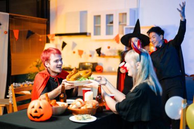 Neşeli ofis Cadılar Bayramı partisi kostüm giymiş iş arkadaşlarıyla, içkiler ve kahkahalarla kutlama, takım çalışmasını teşvik etme ve şenlik ruhu.