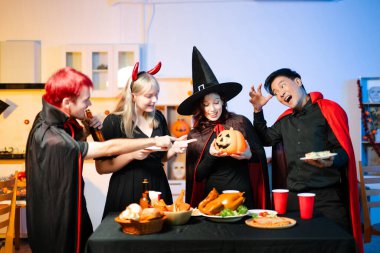 Cadılar Bayramı kostümlü bir grup genç arkadaş kapalı bir partide yemek ve içkinin tadını çıkarıyorlar. Gerçek insanlar eğlence, ürkütücü titreşimler, kırmızı bardaklar ve balkabağı dekoru ile kutluyor..